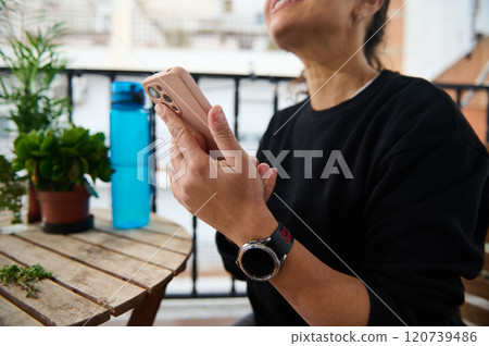 Woman enjoys a moment of relaxation on the balcony with smartphone 120739486