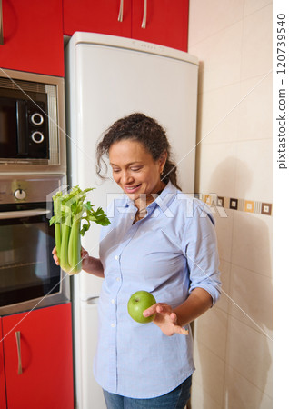 Woman enjoying healthy lifestyle in her kitchen with fresh produce Woman enjoying healthy lifestyle in her kitchen with fresh produce 120739540