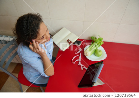 Woman planning healthy diet with tablet and notebook at home 120739564