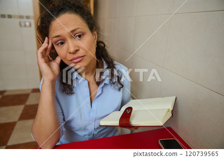 Thoughtful woman holding a journal in a pensive moment 120739565