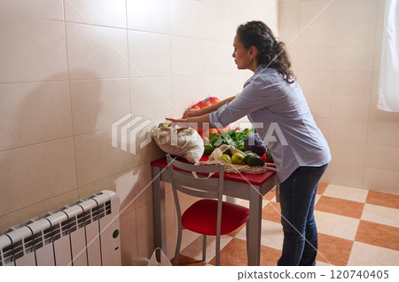 Woman organizing fresh produce on kitchen table at home Woman organizing fresh produce on kitchen table at home 120740405