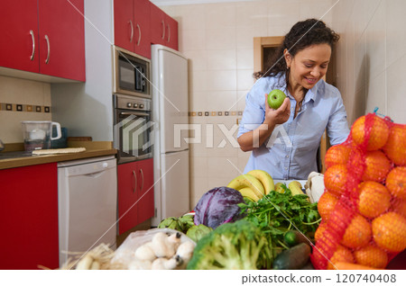 Woman in kitchen preparing fresh fruits and vegetables Woman in kitchen preparing fresh fruits and vegetables 120740408