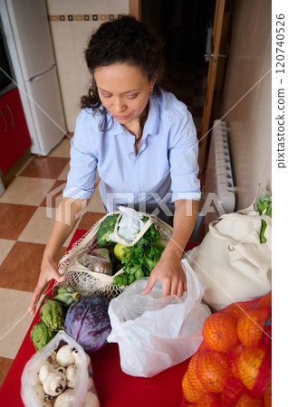 Woman organizing fresh vegetables on kitchen table Woman organizing fresh vegetables on kitchen table 120740526