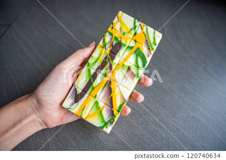 Trend Dubai white chocolate with pistachio paste and kataifi dough in woman hand. Confectionery handmade sweets at home in the kitchen.  120740634