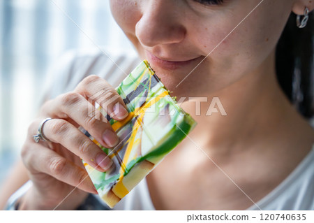 Woman eating trend Dubai white chocolate with pistachio paste and kataifi dough. Confectionery handmade sweets at home in the kitchen.  120740635