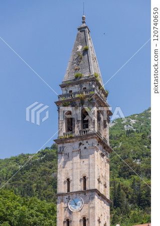 Historic bell tower of Perast rises above green hills under clear blue sky Historic bell tower of Perast rises above green hills under clear blue sky 120740650