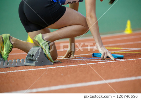 Runner preparing at starting blocks for a relay race during a track event 120740656