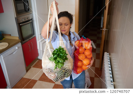 Woman holding groceries in a kitchen with fresh produce Woman holding groceries in a kitchen with fresh produce 120740707