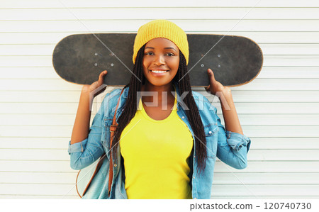 Fashion portrait happy smiling young african woman with skateboard in colorful clothes Fashion portrait happy smiling young african woman with skateboard in colorful clothes 120740730