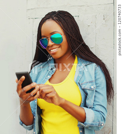 Fashion pretty smiling african woman using smartphone in the city 120740733