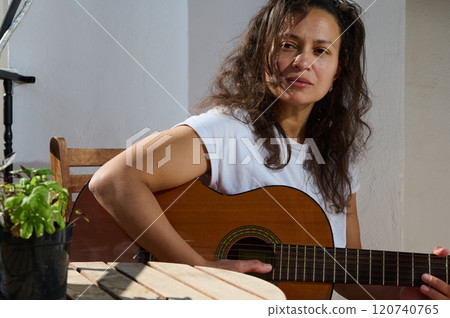 Woman enjoying a sunny day playing acoustic guitar outdoors Woman enjoying a sunny day playing acoustic guitar outdoors 120740765