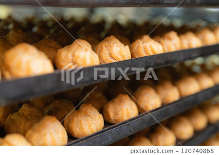 Rows of profiterole blanks lying on a cart from the oven 120740868