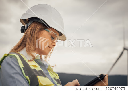 A skilled female engineer monitors wind turbines for efficiency and safety, playing a key role in sustainable energy initiatives and driving environmental innovation in the industry 120740975