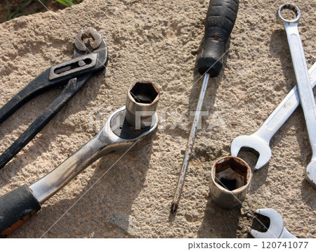 Automotive tools: ratchet, captive horn wrenches, screwdrivers, pliers, tongs on a concrete surface background. Garage and workshop. Automotive mechanics, engineering, manufacturing, industry 120741077