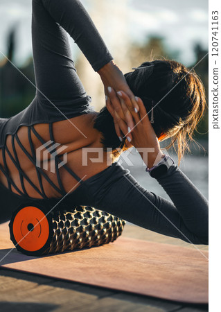 active fitness woman practicing muscular relaxation exercise with massaging foam roller, person stretching with fascial release equipment after sports training, back pain and body stiffness release active fitness woman practicing muscular relaxation exercise with massaging foam roller, person stretching with fascial release equipment after sports training, back pain and body stiffness release 120741163