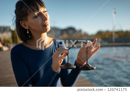 person holding tibetian tingsha bell instrument for vibration and sound healing therapy, ting-sha cymball body and mind recovery technique, woman meditation and spirituality concept 120741175