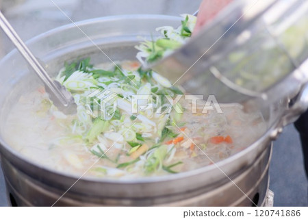 A scene of adding spring onions to pork soup simmered in a large pot A scene of adding spring onions to pork soup simmered in a large pot 120741886