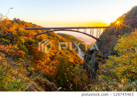 福島縣福島市，連接高湯溫泉和土湯關的萬代東天際線，日出時津巴庫穀不動澤橋的秋葉和晨光 120745463