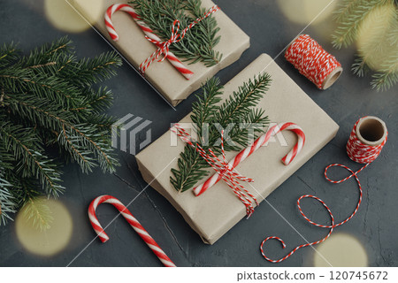 Gift boxes in craft paper with candy canes and coniferous tree Gift boxes in craft paper with candy canes and coniferous tree 120745672