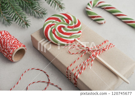 Gift box wrapped in craft paper with green and red lollipop 120745677