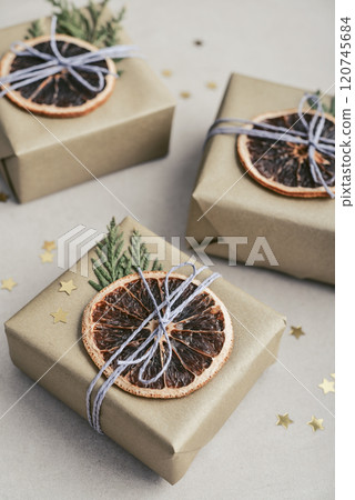 Gifts boxes in golden paper with dry oranges Gifts boxes in golden paper with dry oranges 120745684