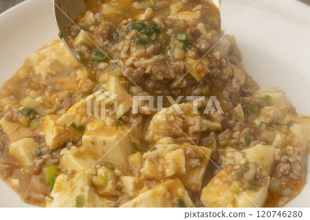 Ladle the mapo tofu onto a plate. 120746280