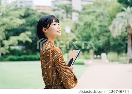 Smiling university student with campus in the background 120746724