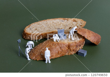 Miniature figurines dressed as forensic investigators examining bread slices with equipment 120749650