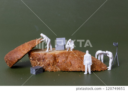 Miniature figurines dressed as forensic investigators examining bread slices with equipment 120749651