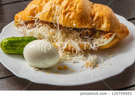 Croissant sandwich with tuna, egg, cucumber on a white plate, close up view Croissant sandwich with tuna, egg, cucumber on a white plate, close up view 120749983