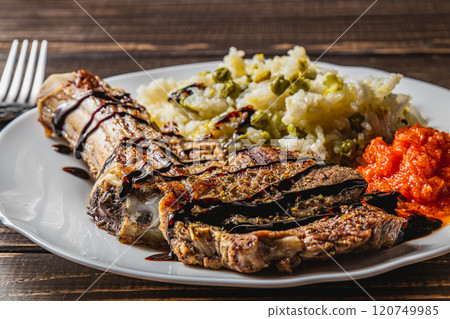 entrecote on the bone with rice and vegetables and adjika on a white plate entrecote on the bone with rice and vegetables and adjika on a white plate 120749985