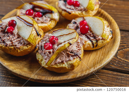 toast with chicken liver pate with pear, cranberry and sauce on a wooden plate 120750016