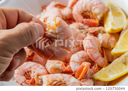 Tiger king prawns cooked and seasoned with lemon, close up in a man's fingers Tiger king prawns cooked and seasoned with lemon, close up in a man's fingers 120750044
