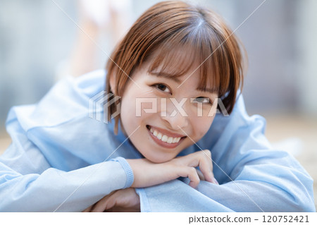 一個留著短鮑伯的年輕女子躺在地板上 120752421