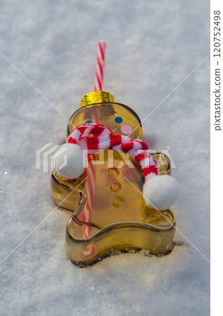 Festive gingerbread man glass bottle with striped straw and scarf lying on snow . High quality photo Festive gingerbread man glass bottle with striped straw and scarf lying on snow . High quality photo 120752498