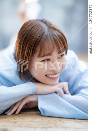 一個留著短鮑伯的年輕女子躺在地板上 120752572