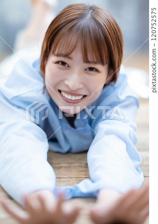 A young woman with a short bob lying on the floor 120752575