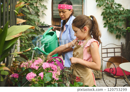 Mother and daughter gardening together with watering cans 120753299