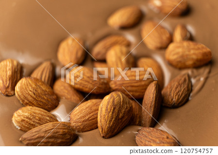 Almond nuts in melted milk chocolate macro Almond nuts in melted milk chocolate macro 120754757