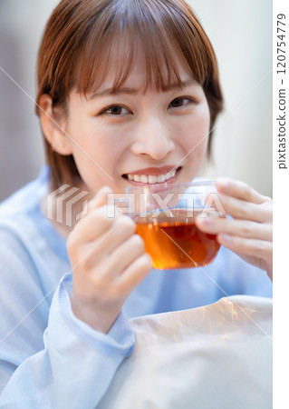 A young woman with a feminine look drinking tea A young woman with a feminine look drinking tea 120754779
