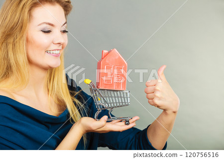 Woman holding shopping cart with house inside 120756516