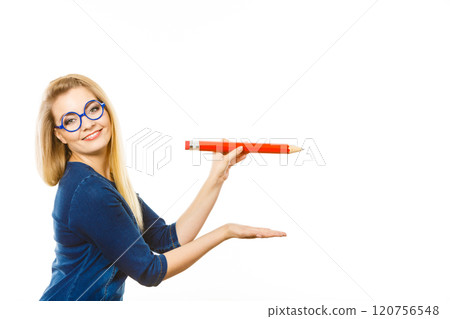 Positive woman holds big pencil in hand Positive woman holds big pencil in hand 120756548