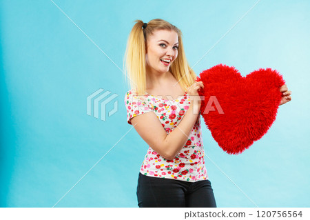 Happy woman holding heart shaped pillow Happy woman holding heart shaped pillow 120756564