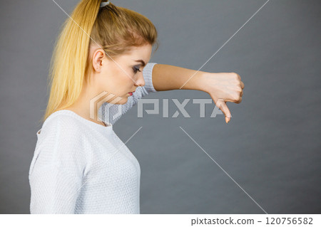 Sad woman showing thumb down gesture 120756582