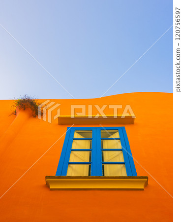 A Stunning and Vibrant Orange Wall Featuring a Blue Window Set Against a Clear Blue Sky in a Capri island A Stunning and Vibrant Orange Wall Featuring a Blue Window Set Against a Clear Blue Sky in a Capri island 120756597
