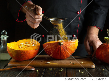 A skilled chef expertly sifts spices onto fresh pumpkin halves in a dimly lit kitchen. The warmth of the wood surrounds a culinary adventure, celebrating seasonal flavors and creativity A skilled chef expertly sifts spices onto fresh pumpkin halves in a dimly lit kitchen. The warmth of the wood surrounds a culinary adventure, celebrating seasonal flavors and creativity 120756944