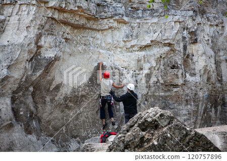 Climber prepares for ascent while belayer ensures safety in stunning rocky landscape Climber prepares for ascent while belayer ensures safety in stunning rocky landscape 120757896