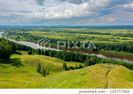 Beautiful view of the Klyazma River winding through lush hills and greenery in Gorokhovets under a blue sky Beautiful view of the Klyazma River winding through lush hills and greenery in Gorokhovets under a blue sky 120757962