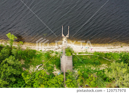 Relaxing waterside retreat with a wooden dock overlooking tranquil waters and lush greenery on a serene day Relaxing waterside retreat with a wooden dock overlooking tranquil waters and lush greenery on a serene day 120757978