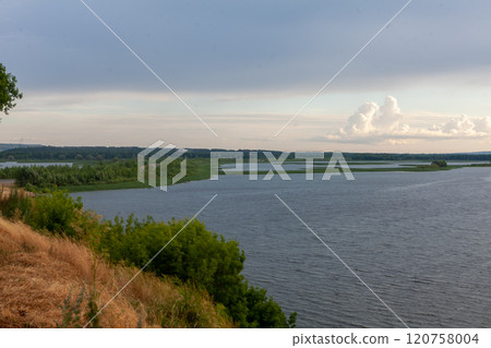 Winding curves of the Vilga River showcase natures beauty under a dramatic sky Winding curves of the Vilga River showcase natures beauty under a dramatic sky 120758004